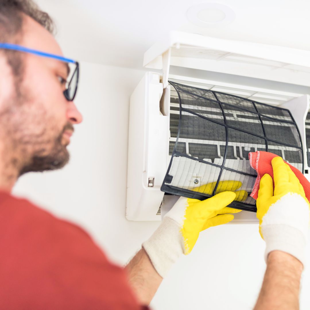 man cleaning a filter on a AC unit