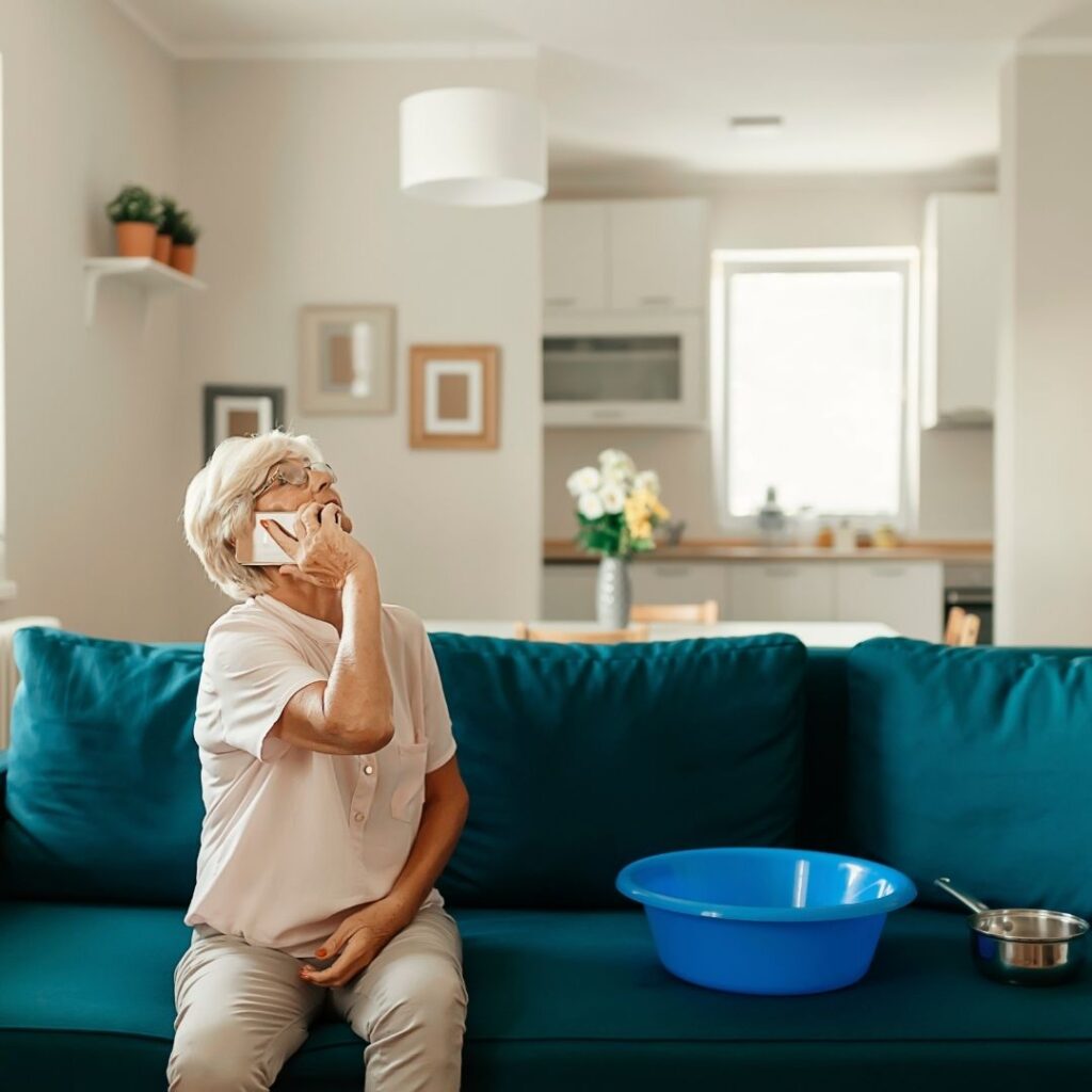 old woman on the phone as she watches ceiling leak