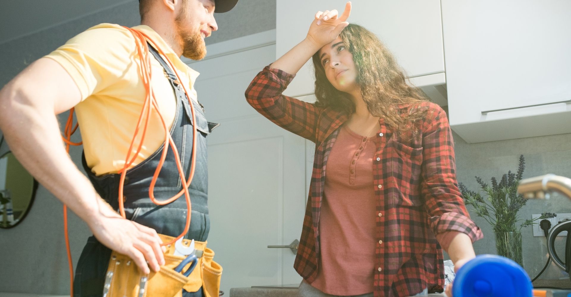 woman with hand on head talking to plumber holding plunger
