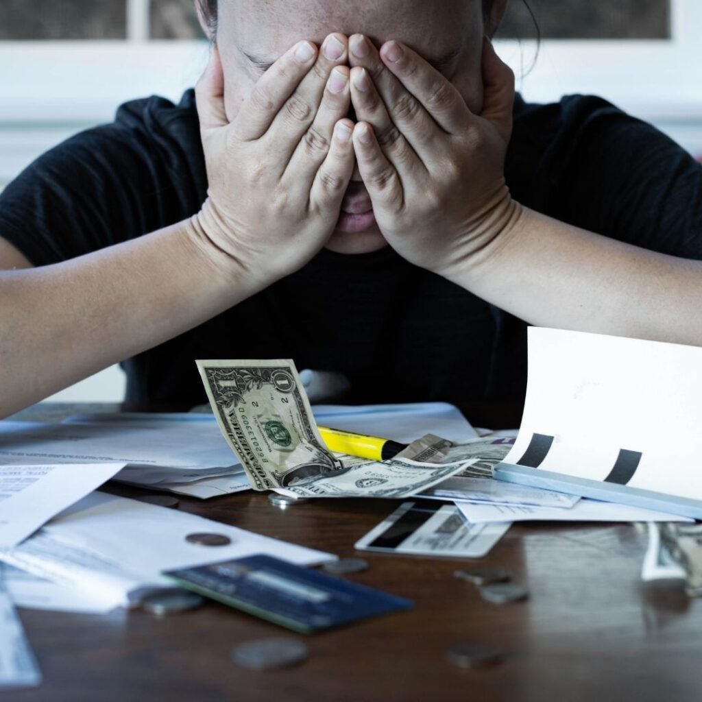 person covering their eyes as they pay bills