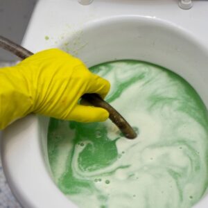 gloved hand holding tube in toilet