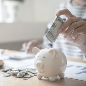 Closeup of someone putting money into a piggy bank