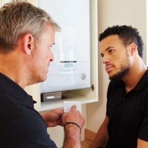 Two people talking near a furnace in a home