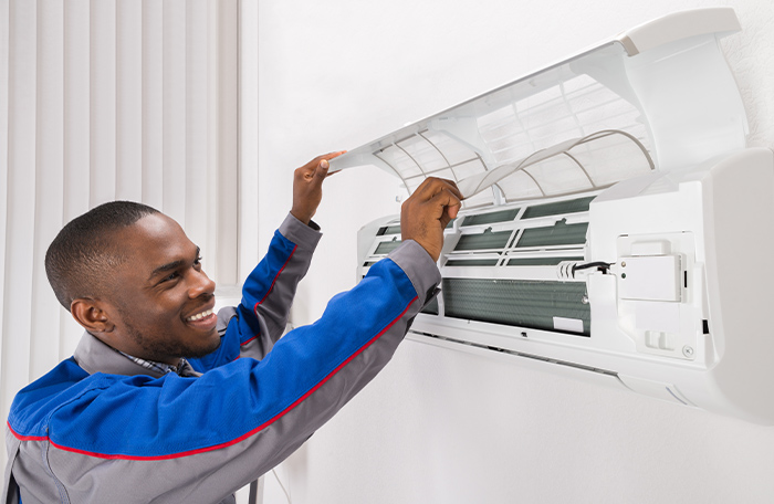 a professional looking at the inside of a wall ac unit