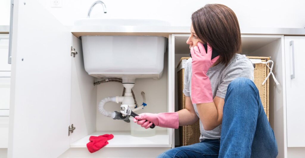 woman with a plumbing emergency calling a plumber
