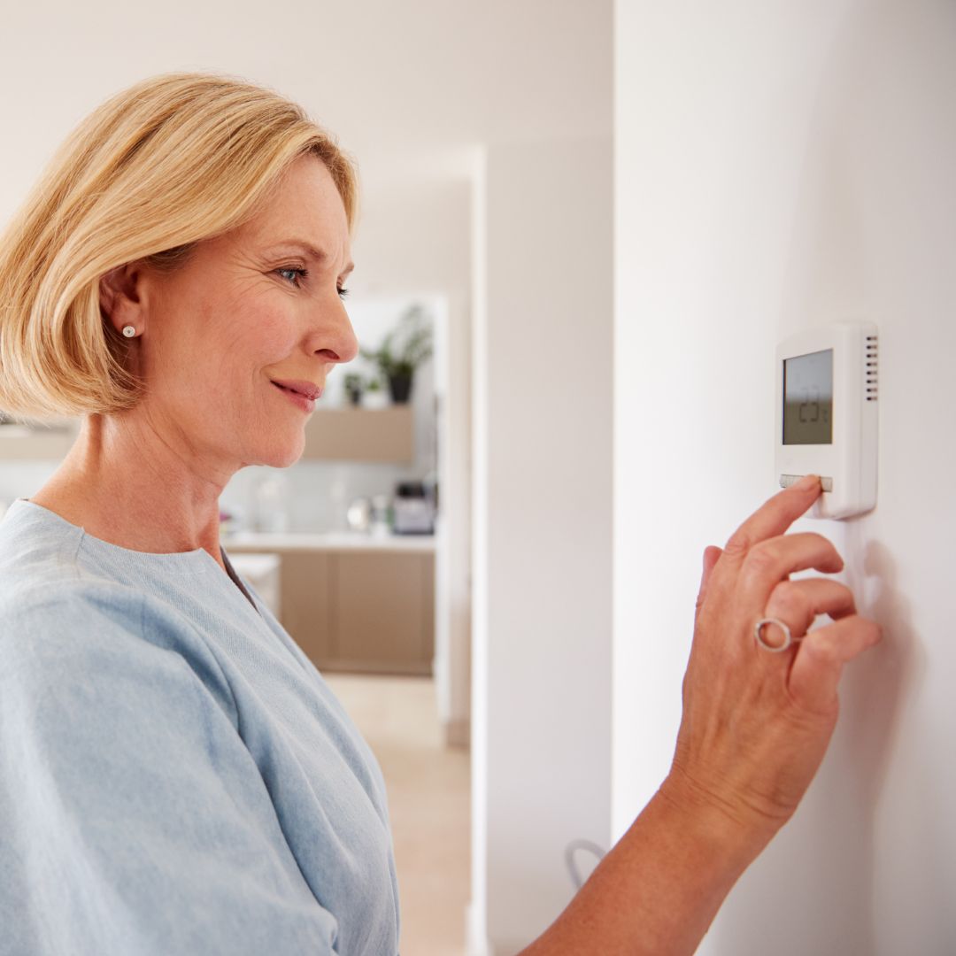 woman adjusting thermostat