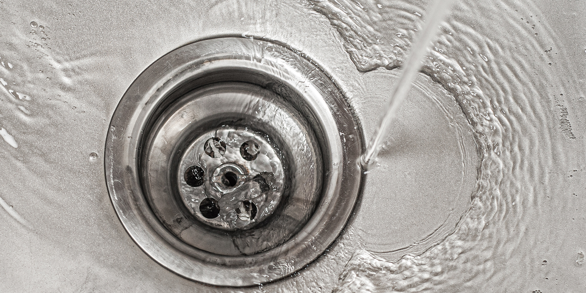 Water flows into the stainless steel kitchen sink drain