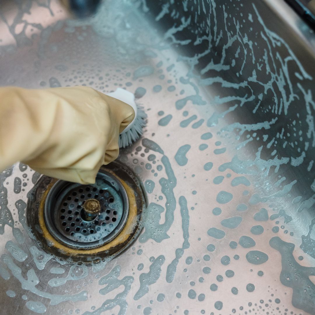 a person scrubbing around a drain