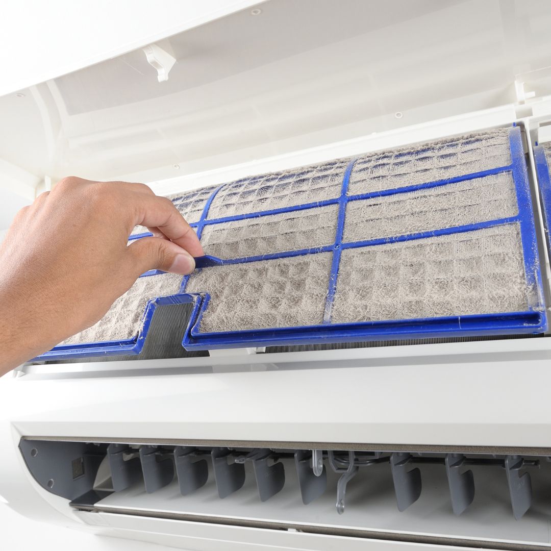 A person taking out their dirty AC filter