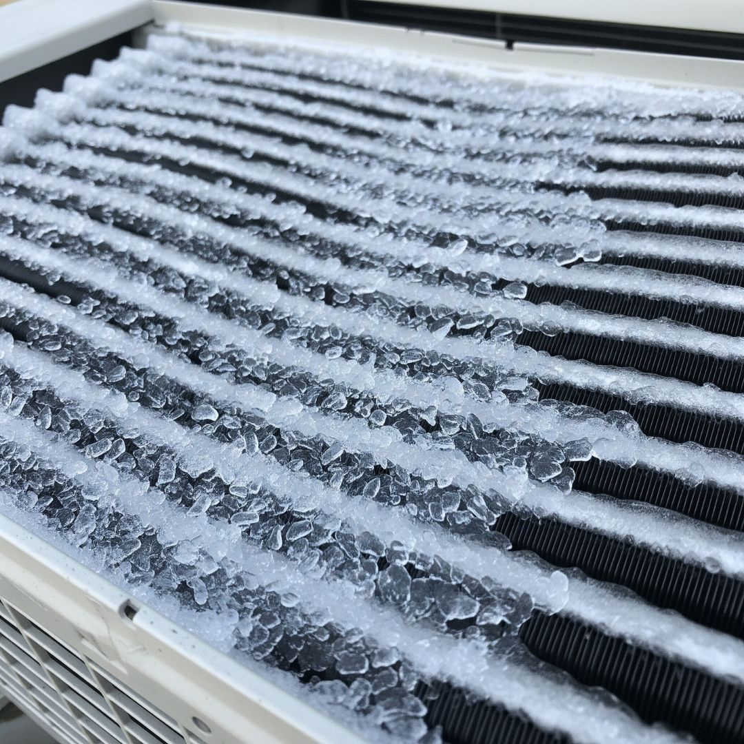 A close-up view of ice built up on an air conditioner's evaporator coils.