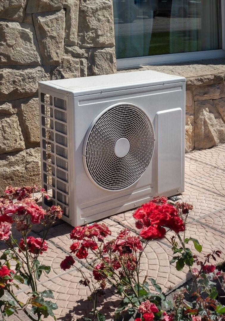 lone AC fan cabinet beside a flower bed